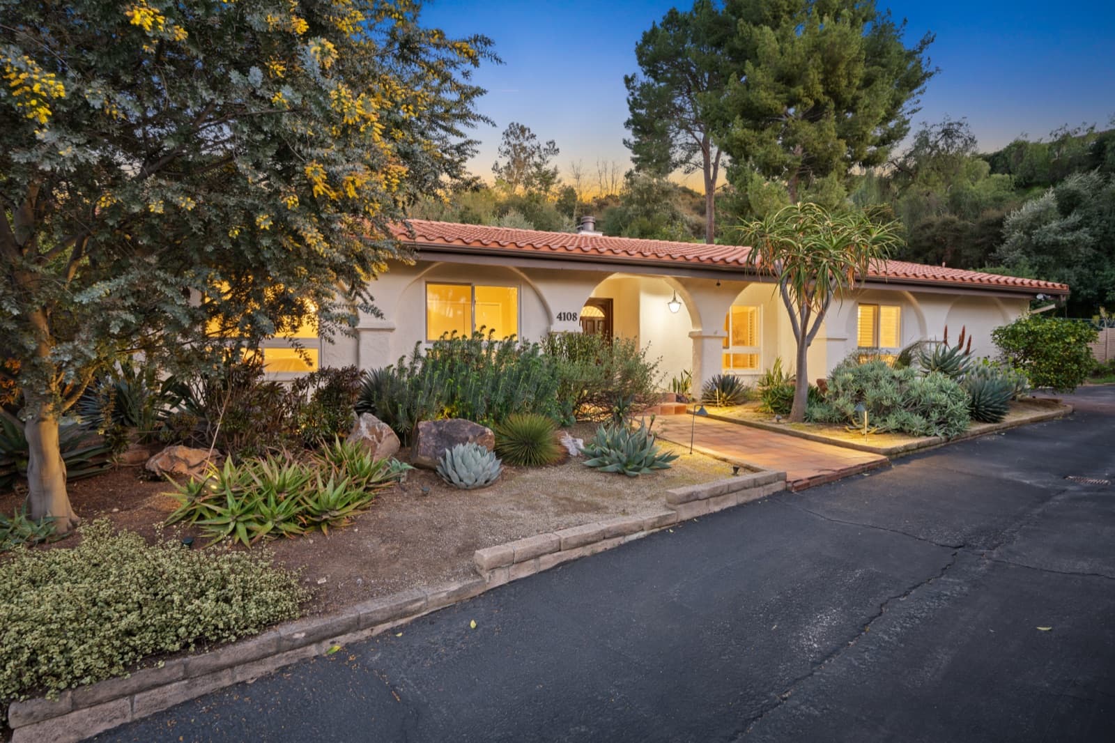 Dusk exterior of a single-story Spanish-style home at 4108 Monet Ave with desert landscaping